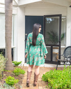 Taylor Mini Dress featuring a vibrant floral print on a green base with flared sleeves