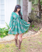 Taylor Mini Dress featuring a vibrant floral print on a green base with flared sleeves