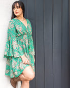 Taylor Mini Dress featuring a vibrant floral print on a green base with flared sleeves